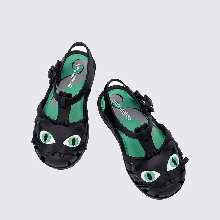 Sandália infantil Mini Melissa Possession Cat Baby nas cores preto e verde, com aplicação divertida de rosto de gatinho no cabedal. Confeccionada em Melflex, possui tiras vazadas, fecho lateral com fivela e solado confortável. Perfeita para looks lúdicos e estilosos no dia a dia.

Palavra-chave principal: Mini Melissa Possession Cat Baby
Palavras-chave relacionadas: sandália gatinho infantil, Melflex, preto e verde, fecho com fivela, calçado confortável, visual divertido, sandália baby.
