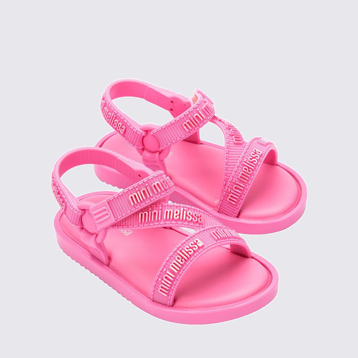 "Sandália infantil Mini Melissa Stripes M.Lover Baby na cor rosa, com tiras cruzadas, solado reto e fecho em velcro. Produzida em Melflex, é leve, macia e confortável, ideal para os primeiros passos com segurança, estilo e delicadeza