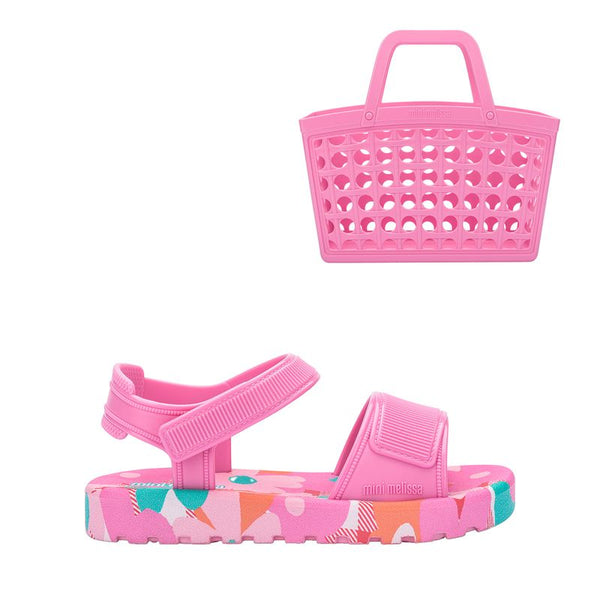 Sandália Melissa Sun Cruise adulta na cor rosa, com acabamento brilhante e translúcido. Feita em material Melflex, possui design moderno com tiras largas cruzadas sobre o pé e fechamento prático ajustável. Solado rasteiro, leve e confortável, perfeito para criar looks casuais e estilosos para o dia a dia. Acompanha uma bolsa rosa de 5 litros