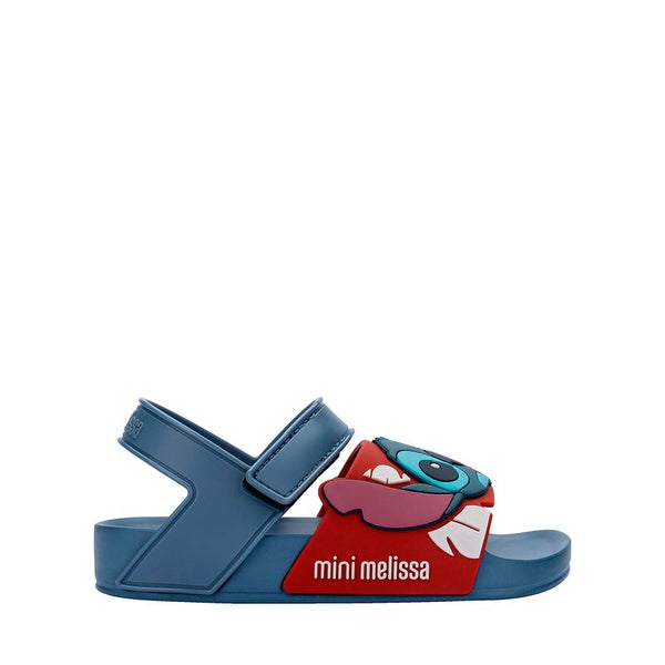 Sandália infantil Mini Melissa Flowing Sandal Stitch Baby nas cores azul e vermelho, com aplique do personagem Stitch na parte frontal. Feita em Melflex, possui tiras largas, fechamento em velcro e solado confortável, perfeita para os pequenos fãs da Disney