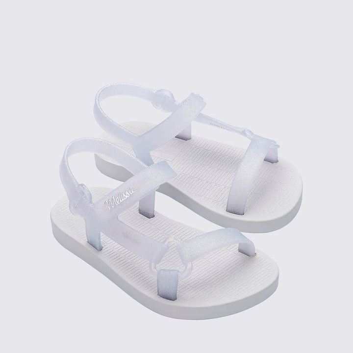 Sandália infantil Mini Melissa Sun Downtown Baby na cor branco com efeito vidro e glitter, acabamento brilhante e design unissex. Feita em Melflex, é leve, confortável e possui fechamento em velcro, garantindo segurança e estilo para os pequenos