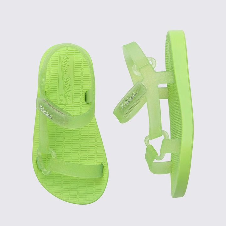 Sandália infantil Mini Melissa Sun Downtown Baby na cor verde com glitter, acabamento brilhante e design unissex. Produzida em Melflex, é leve, confortável e possui fechamento em velcro para mais segurança. Ideal para dias ensolarados e combinações