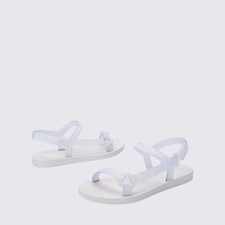 Mini Melissa Sun Downtown II 36099 na versão Branco/Vidro com acabamento glitterizado é perfeita para as pequenas que amam estar estilosas até nos momentos mais simples Leve (só 290g!) e feita em Melflex, essa sandália é flexível, durável e superconfortável. O design moderno combinado com o brilho sutil do glitter